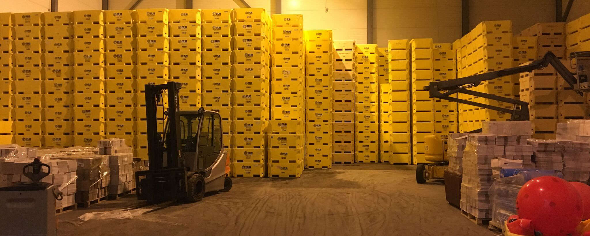 Lager med gule fiskekar og gaffeltruck